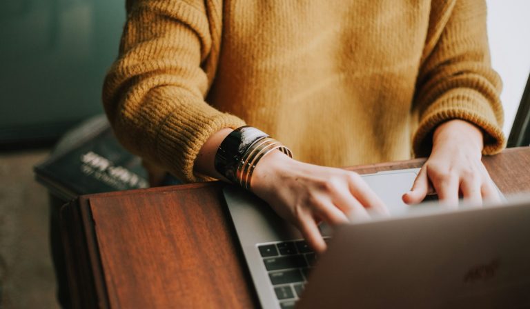 Person travaillant sur un ordinateur portable, main droite sur le clavier, portant un bracelet.